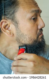 Asian Man Shaving Beard With Electric Razor Machine.