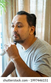 Asian Man Shaving Beard With Electric Razor Machine.