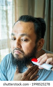 Asian Man Shaving Beard With Electric Razor Machine.