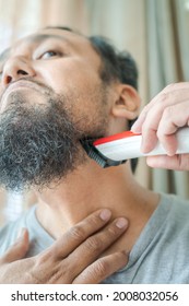 Asian Man Shaving Beard With Electric Razor Machine.