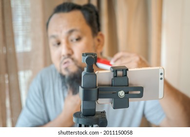 Asian Man Shaving Beard With Electric Razor Machine.