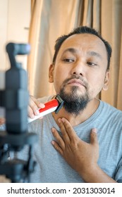 Asian Man Shaving Beard With Electric Razor Machine.