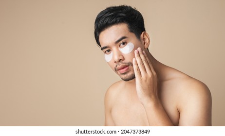Asian Man Shirtless Show Patches Mask Under Eyes For Anti Wrinkles And Eye Dark Circles On Face. Isolated On Brown Color Background.