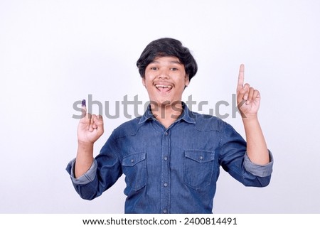 Asian man showing finger after voting on Indonesia presidential election and pointing up to the empty space for text 