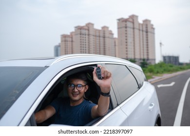 Asian Man Shows Off The Key Of An Innovative Electric Car