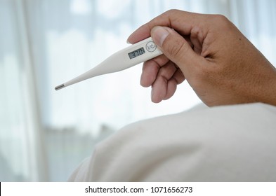 Asian Man Sick.Monitor Body Temperature With Mercury.Thermometer In Asian Male Hands.