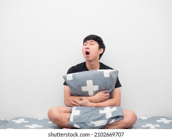 Asian Man Sit On The Bed Hug Pillow Feeling Sleepy And Yawn