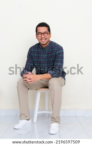 Asian man sitting in a bench while smiling to the camera