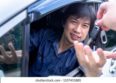 Asian Man Sitting In A Can And Is Going To Start The Engine - The Concept Of Buying A Used Car Or A Rental Car.