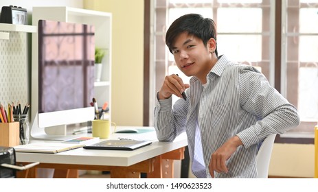 Asian man sitting on home office creative workspace.
