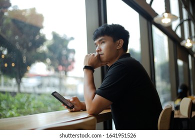 An Asian Man Sitting Vacant In A Coffee Shop
