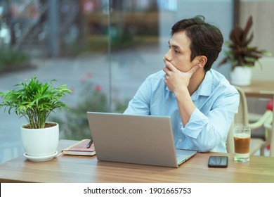 Asian Man Sitting Working Alone At A Coffee Shop
