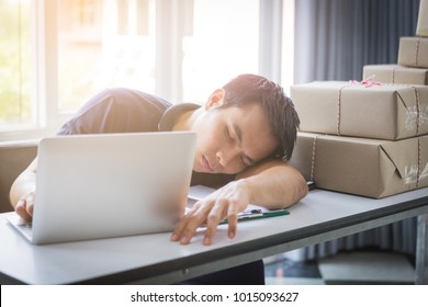 Asian Man Sleep Because Of Woking Hard With Laptop And Postal Parcel Box On White Desk, Selling Online Concept 