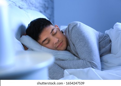 Asian Man Sleeping In Bed At Night