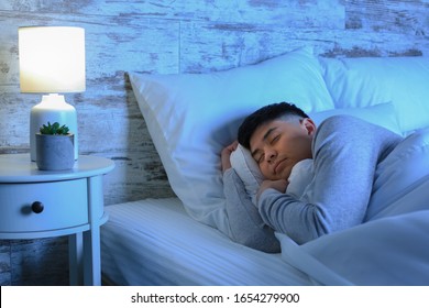 Asian Man Sleeping In Bed At Night