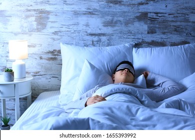 Asian man sleeping in bed at night