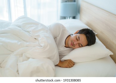 Asian man are sleeping and having good dreams in white blanket in the morning. Rest after work tiring in bedroom at home