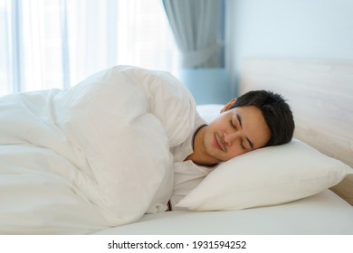 Asian man are sleeping and having good dreams in white blanket in the morning. Rest after work tiring in bedroom at home