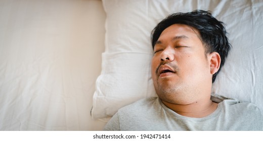 Asian man sleeping on bed with snore face.Concept of snoring.Healthcare medical.Sleep health.Indian man sleep at home.Dream, rest, bed, tired father dad day.Sleep Apnea, Sleep Disordered Breathing.Sdb
