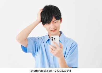 Asian man with the smartphone holding his head in white background - Powered by Shutterstock