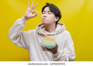 asian man smelling, enjoying, and licking with pleasure delicious noodles. a man gives delicious expressions while eating noodles. - Shutterstock ID 2290203925