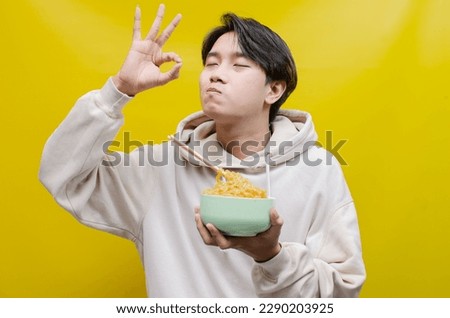 asian man smelling, enjoying, and licking with pleasure delicious noodles. a man gives delicious expressions while eating noodles.