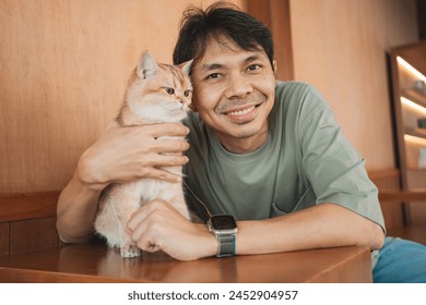 asian man smile and happy during play with his gold british cat in coffee shop - Powered by Shutterstock