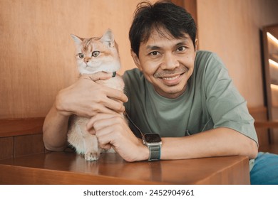 asian man smile and happy during play with his gold british cat in coffee shop - Powered by Shutterstock