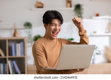 Asian Man Is Smiling And Expressing Happy Feeling On The Computer Laptop Screen. Young Male Got Good News And Show His Cheerful Face.Happiness Men Looking On Laptop Read Message Feel Excited At Home