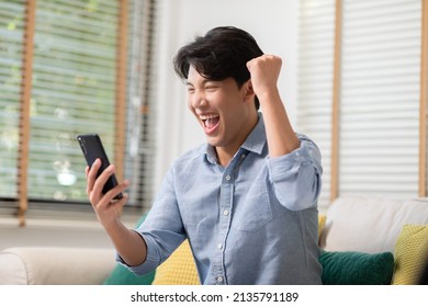 Asian Man Is Smiling And Expressing His Happy Feeling On The Cellphone Screen. He Got Good News And Show His Cheerful Face. Technology Could Helped Us Have More Convenience Connection