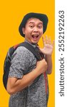 Asian man smiling friendly while holding mobile phone and wearing backpack. smiling happy Asian man wearing backpack say hello to the camera. man with backpack vacation and traveling concept.
