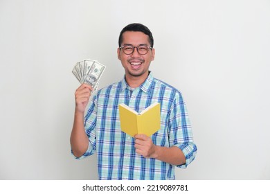 Asian Man Smiling Happy While Holding US Dollar Money And A Book