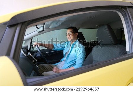 Asian man smiling happy while driving his car