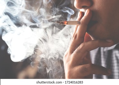 asian man smoking a cigarette smoke spread dark background. concept campaign No smoking and health care.