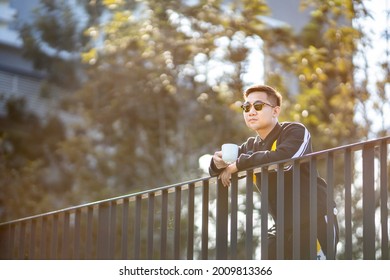 Asian Man In Sportwear Drinking A Cup Of Coffee After Having Morning Exercise With Copy Space