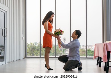 Asian man standing on one knee giving flower to propose his girlfriend on Valentine's day. couple having romantic dating for anniversary or birthday, Love and marriage concept - Powered by Shutterstock