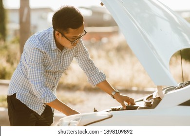 Asian Man Stands In Front Of Car Checking Car Condition After A Broken Car. Broken Car Down On The Road.