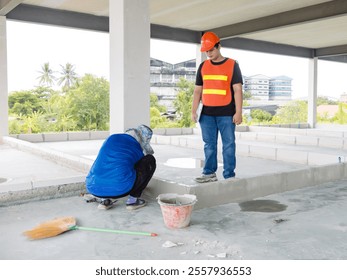 Asian man structural engineer foreman wearing safety gear hard hat high visibility vest checking examine labor workers inspecting progressing work in construction site or building development concept. - Powered by Shutterstock