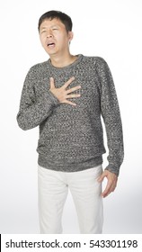 Asian Man Suffering From Heart Attack Or Chest Pain, Hands Holding His Chest In Grey Sweater And White Pants