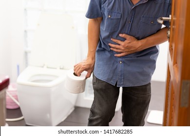 Asian man suffers from diarrhea holding toilet paper near a toilet bowl,man have abdominal pain,stomachache,constipation in bathroom,sick people hand from the belly diarrhea,stomach health problem