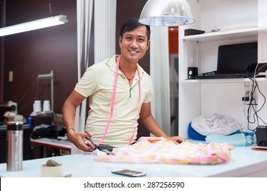 Asian Man Tailor Fashion Clothes Dress Designer Working With Fabric On Table