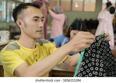 Asian Man Tailor Sitting While Measure The Cloth To Be Sewn At The Clothing Production Room