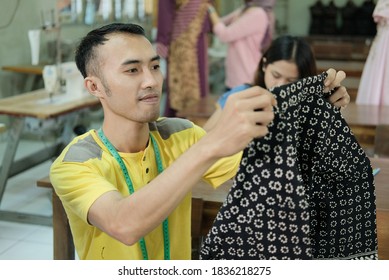 Asian Man Tailor Sitting While Holding The Collar Of The Garment To Be Sewn At The Clothing Production Room