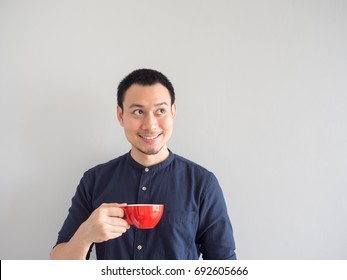 Asian man take a sip of coffee in red cup. - Powered by Shutterstock