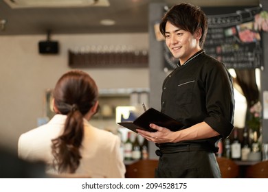 Asian man taking an order at a restaurant - Powered by Shutterstock