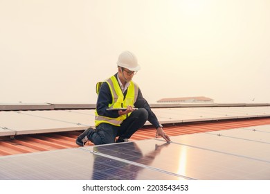 Asian Man Technician Worker In Workplace. Service Engineer Use Tablet Working Inspection In Project Installation Solar Panel On The Roof. Alternative Green Energy. Technology Solar Energy Renewable.