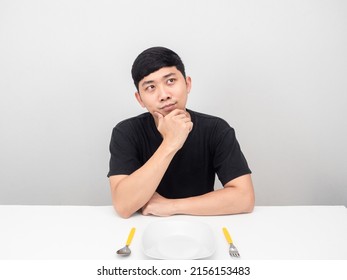 Asian Man Thinking About Dinner At The Table With Cutlery