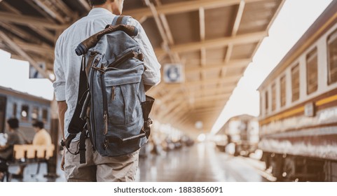 Asian Man Traveler With Backpack In The Railway, Backpack At The Train Station With A Traveler. Travel Concept. Man Traveler Tourist Walking At Train Station.