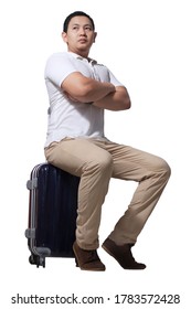Asian man traveler sitting on his suitcase luggage, waiting gesture, wearing casual shirt and backpack, full length portrait isolated on white