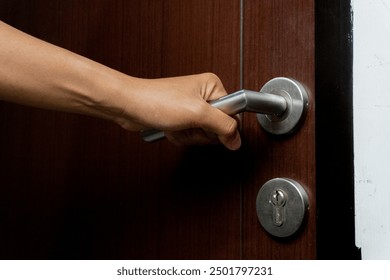 an asian man try to open brown wooden door indoors. door with stainless steel door handle. - Powered by Shutterstock